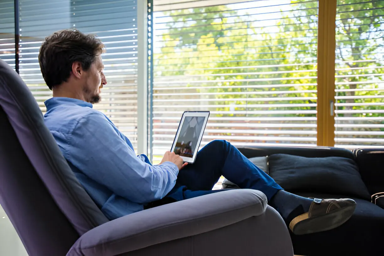 Hombre sentado en su sofa viendo su tablet