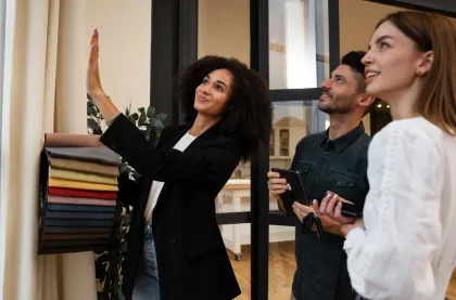 Persona mostrando muestras de tela de cortinas a una pareja en un espacio interior